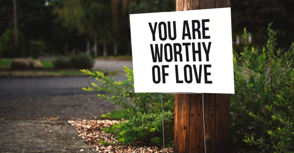 a sign in front of a wooden post that says "you are worth of love"