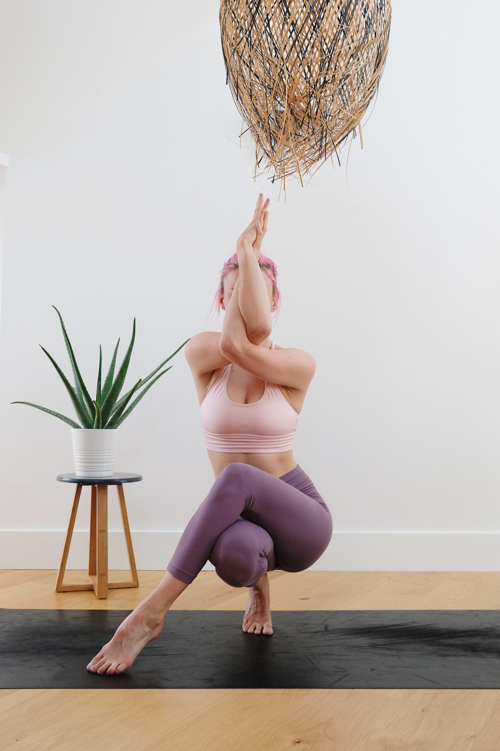 a woman completing a complex yoga pose on a matt.